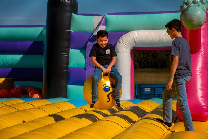 Two children on a yellow inflatable bounce ride at an indoor play center