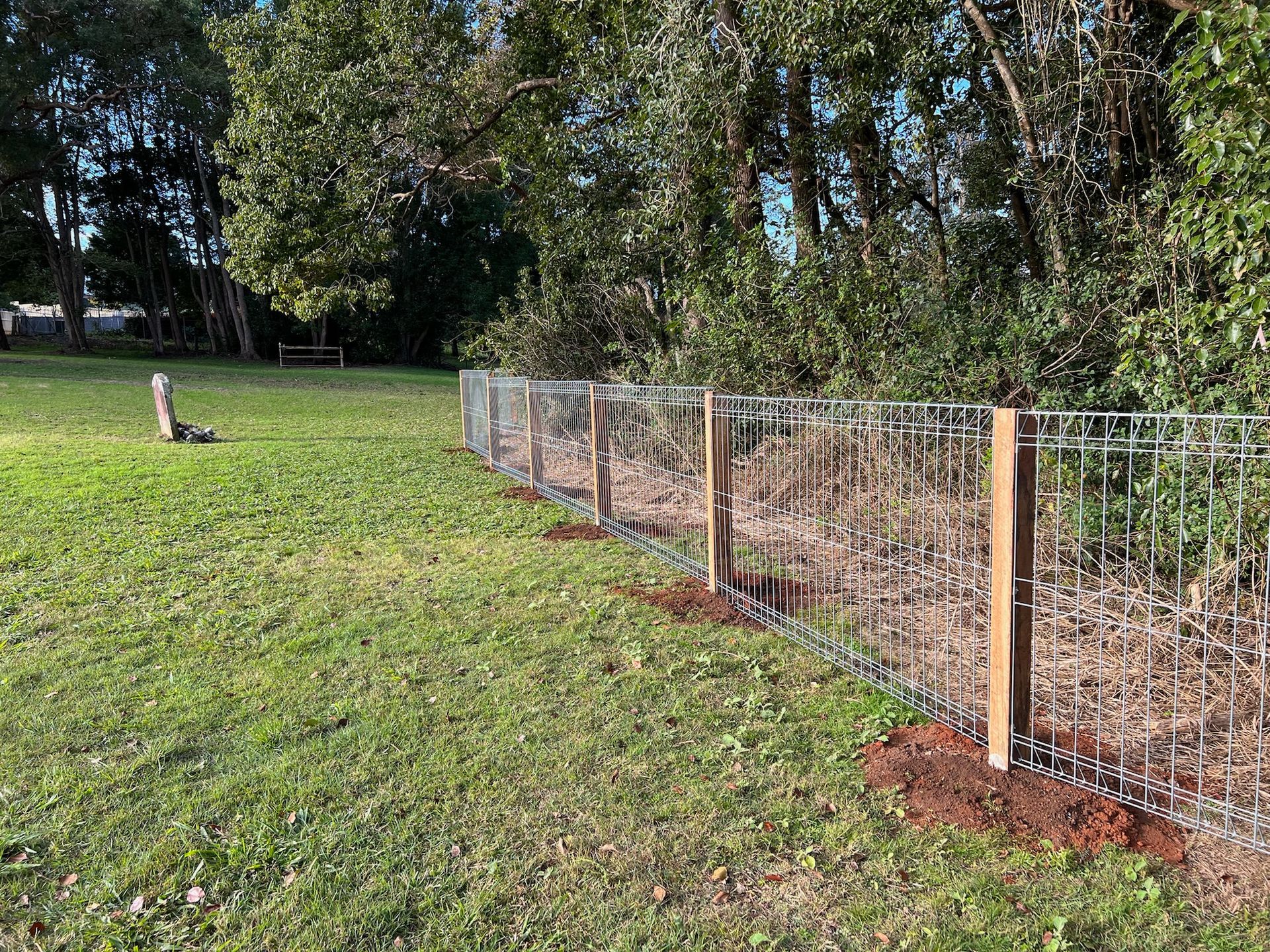 Metal Fence With Wooden Posts in a Grassy Area, Trees in the Background — Fencer Steve In Temagog, NSW