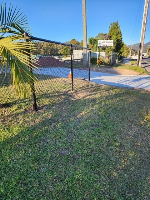 Black Chain-link Fence and Gate Leading to a Building, Grass in the Foreground, Blue Sky — Fencer Steve In Crescent Head, NSW