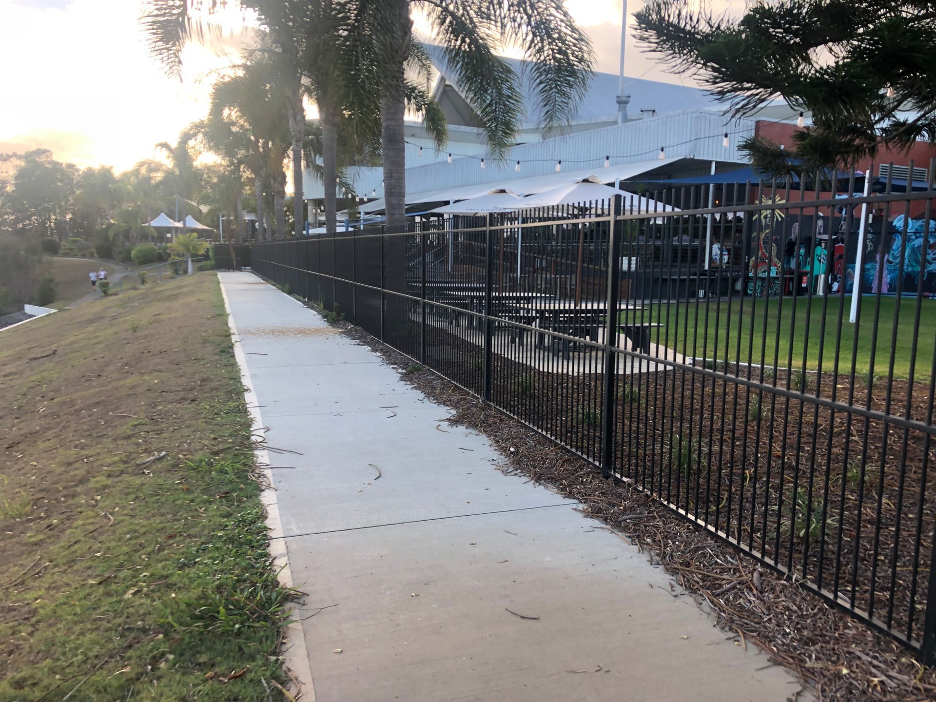 Black Fence Lines a Concrete Path Alongside Grass and a Building — Fencer Steve In Temagog, NSW