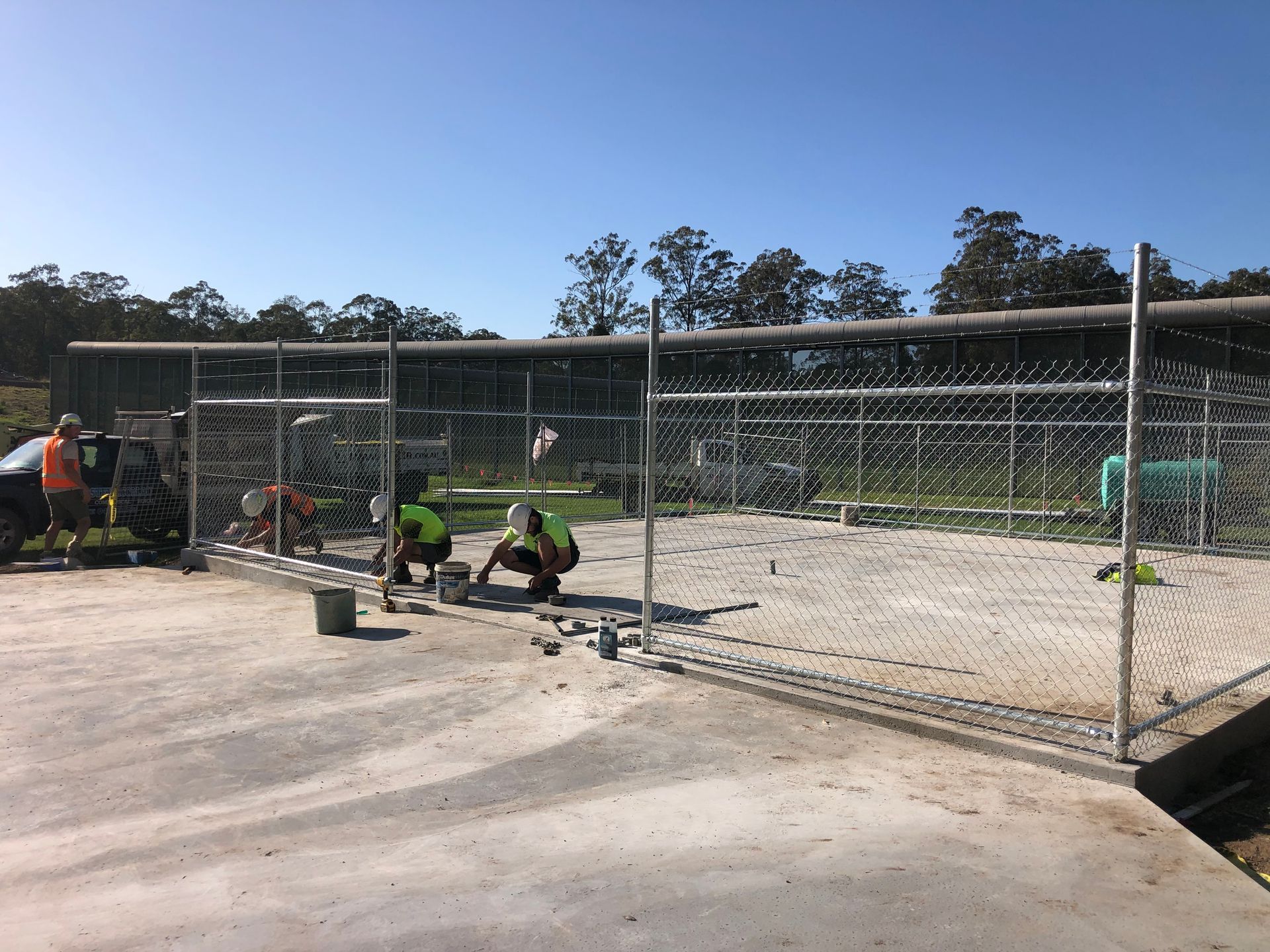 Construction Workers Installing a Chain-link Fence Around a Concrete Structure — Fencer Steve In Temagog, NSW
