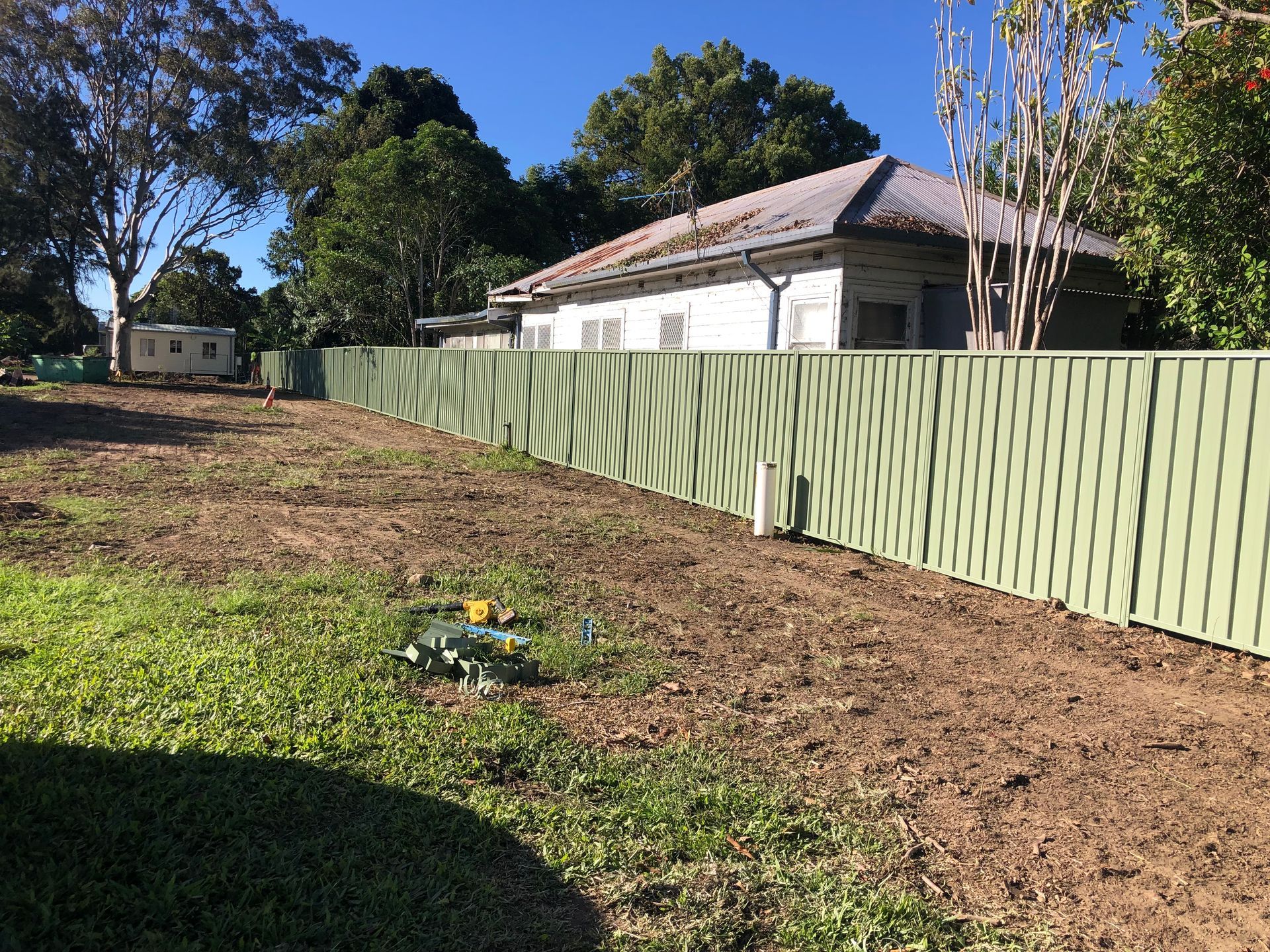 Green fence along a backyard, with a house in the background. Sunny day — Fencer Steve In Temagog, NSW
