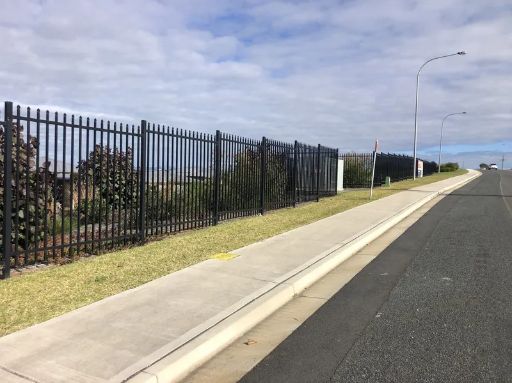 Black Metal Fence Bordering a Sidewalk, Alongside a Street Under a Cloudy Sky — Fencer Steve In South West Rocks, NSW