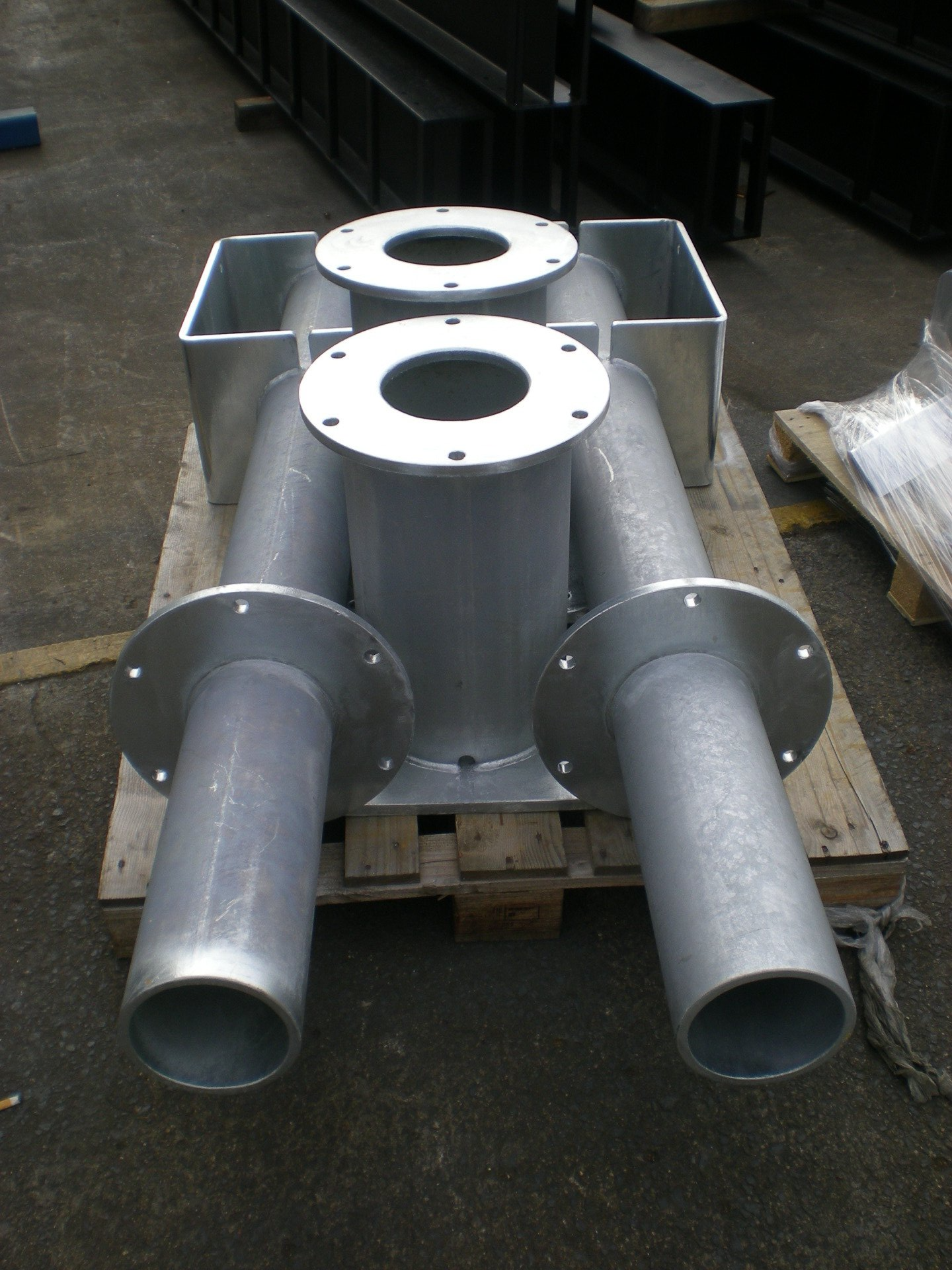 Metal industrial assembly with four cylindrical tubes and two open-top rectangular sections, likely for ventilation.