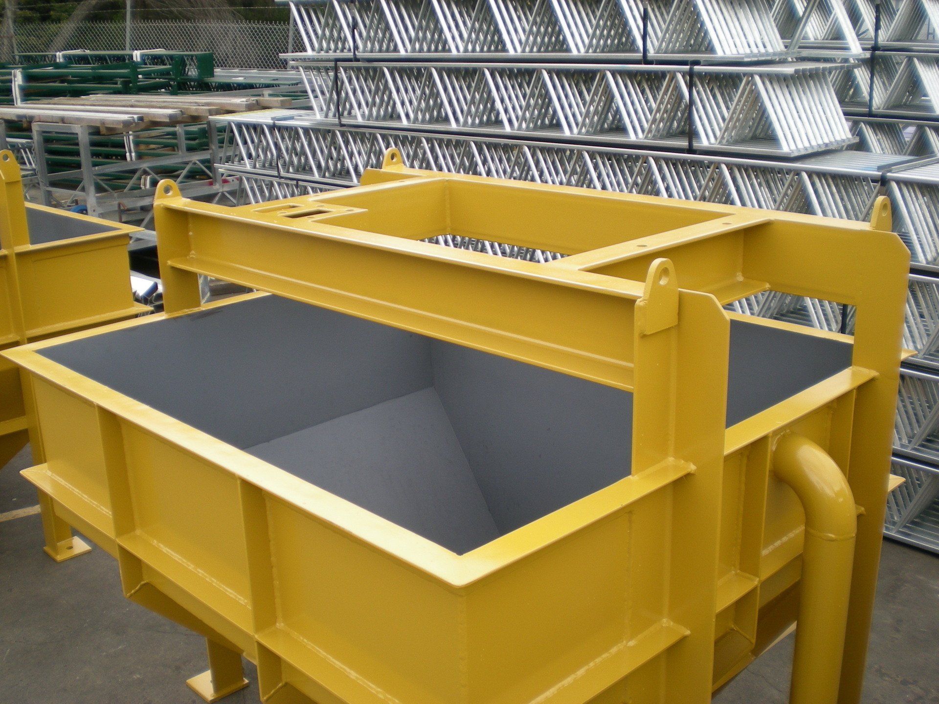 Yellow industrial metal container with a lifting frame, possibly for construction, outdoors.