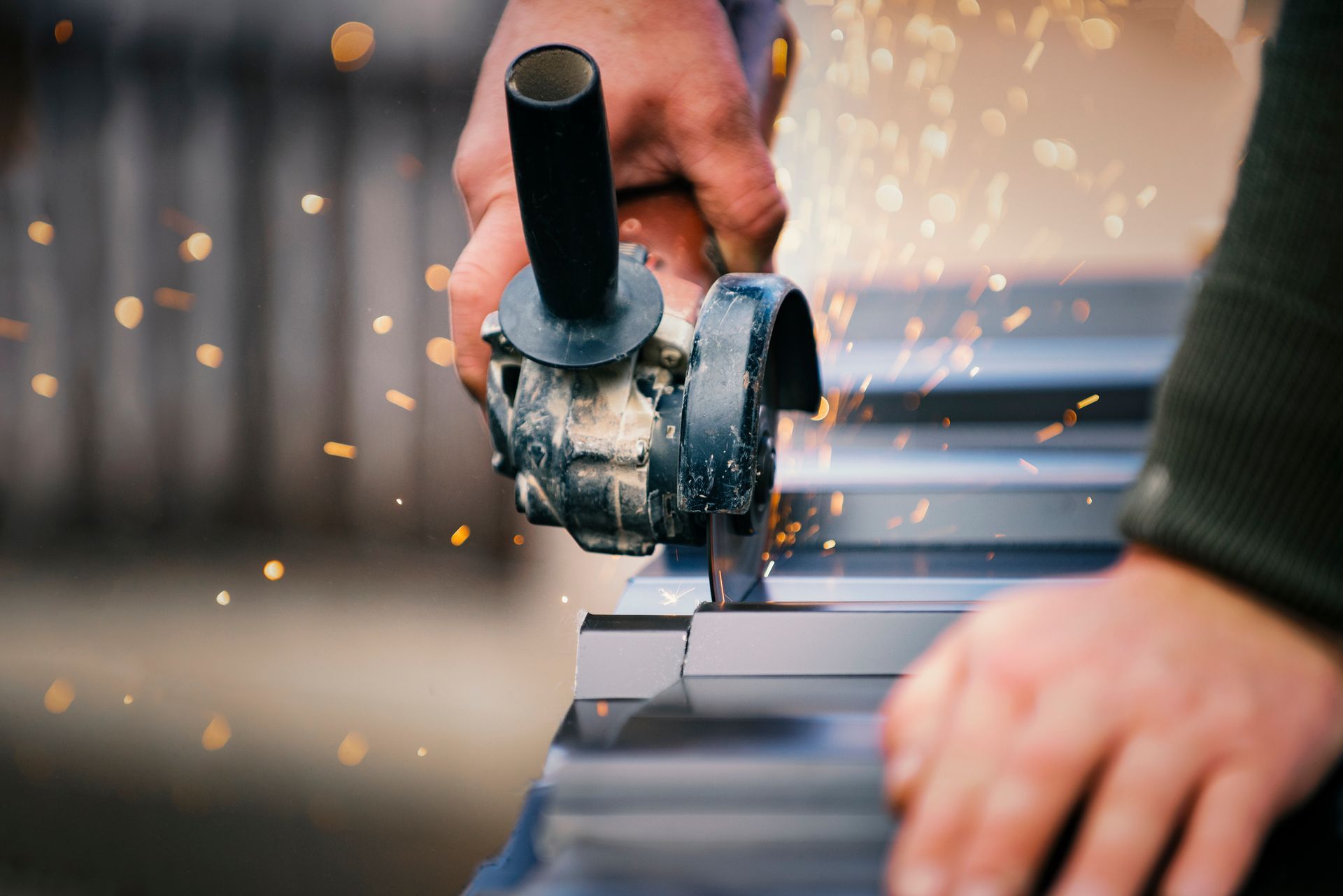 Person cutting metal with angle grinder as sparks fly.