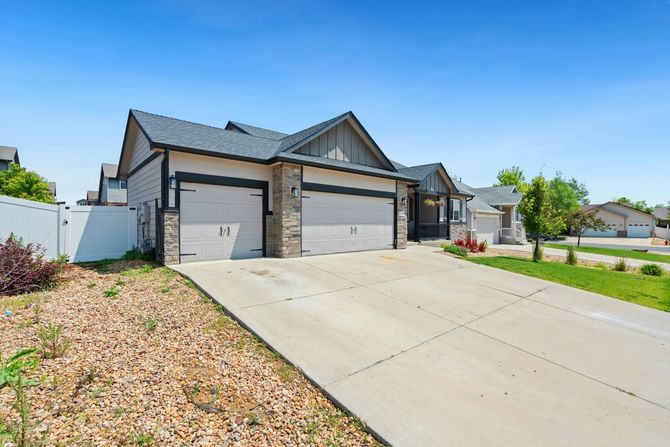 Modern suburban house with three garage doors and a wide driveway under a clear blue sky