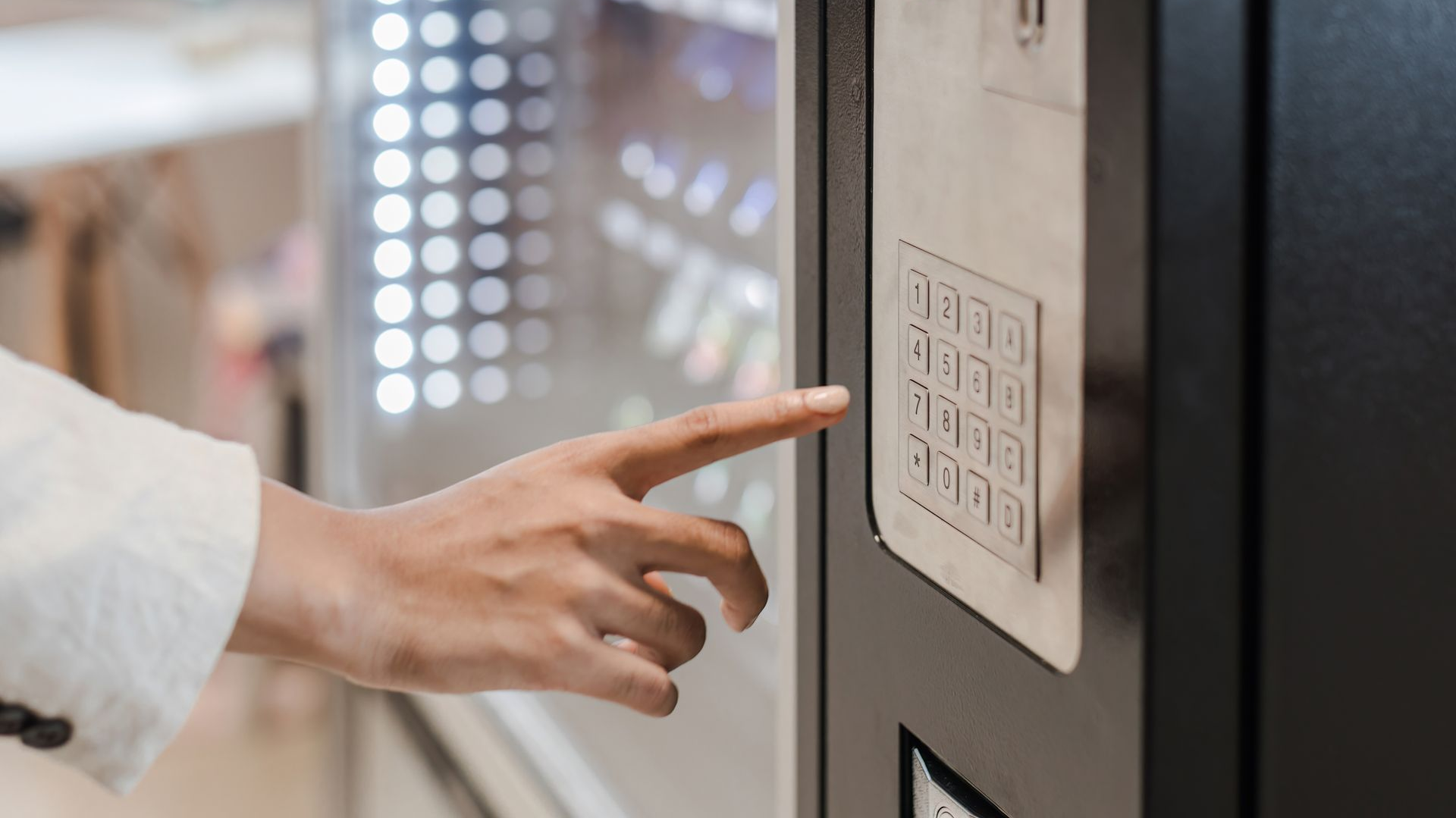 Finger pressing a keypad on a vending machine