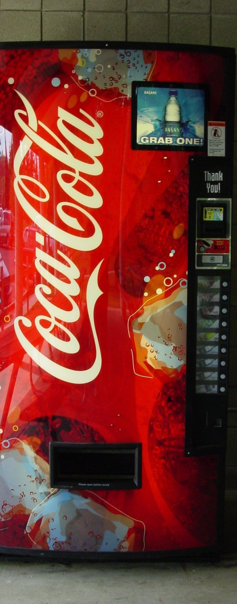 Coca-Cola vending machine with red logo and product display in an indoor hallway