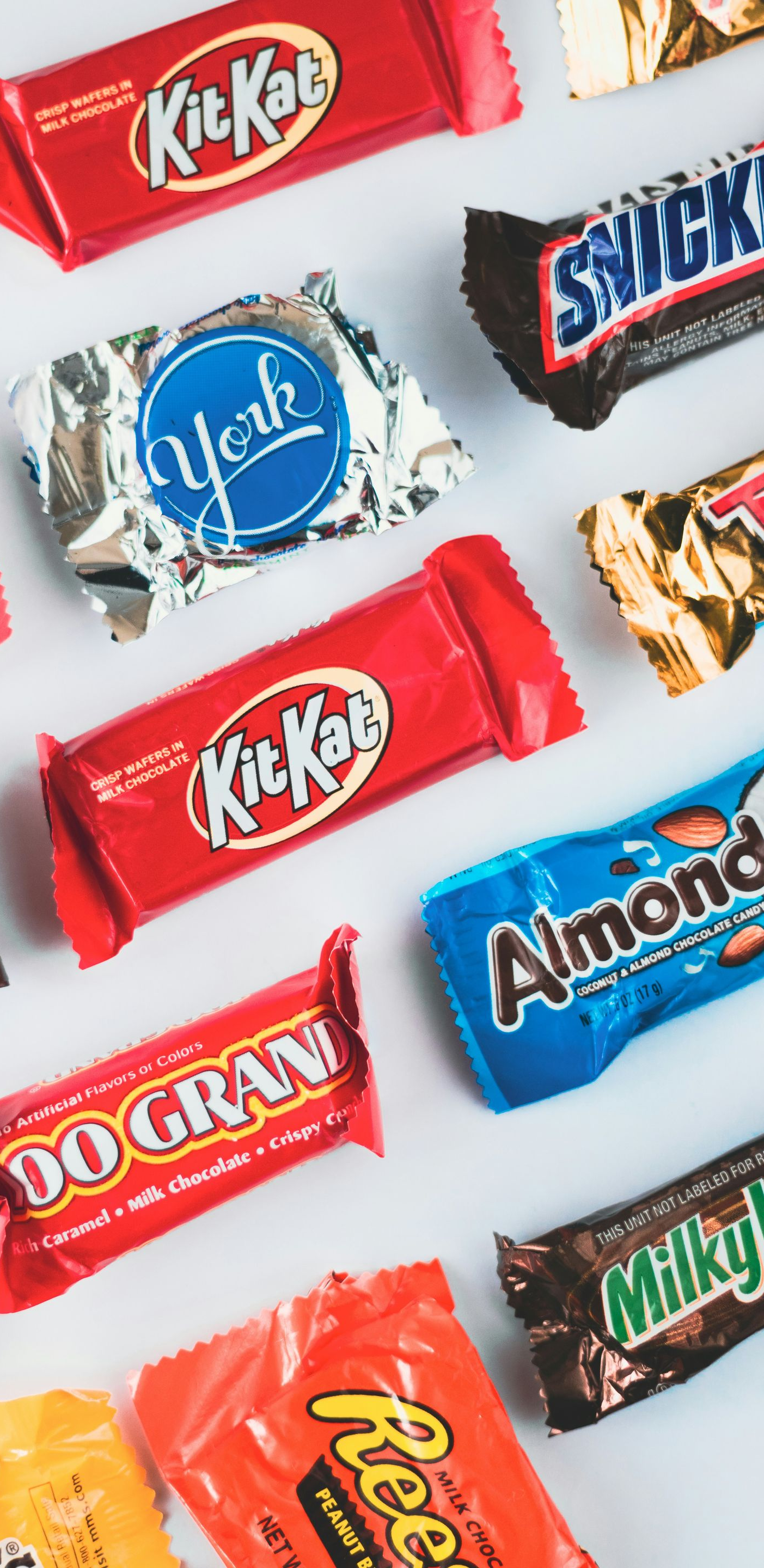 Assorted colorful candy bars scattered on a white background.