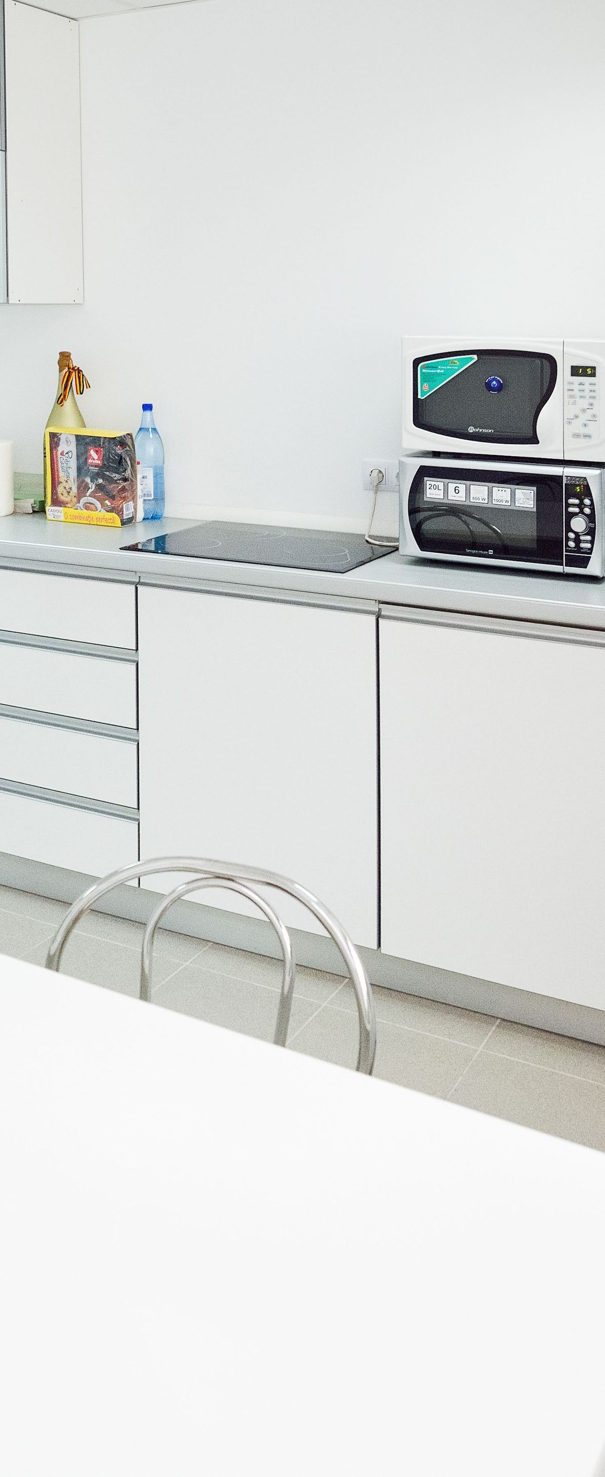 Bright white kitchen counter with sink, cabinets, dishes, and a microwave on the right.