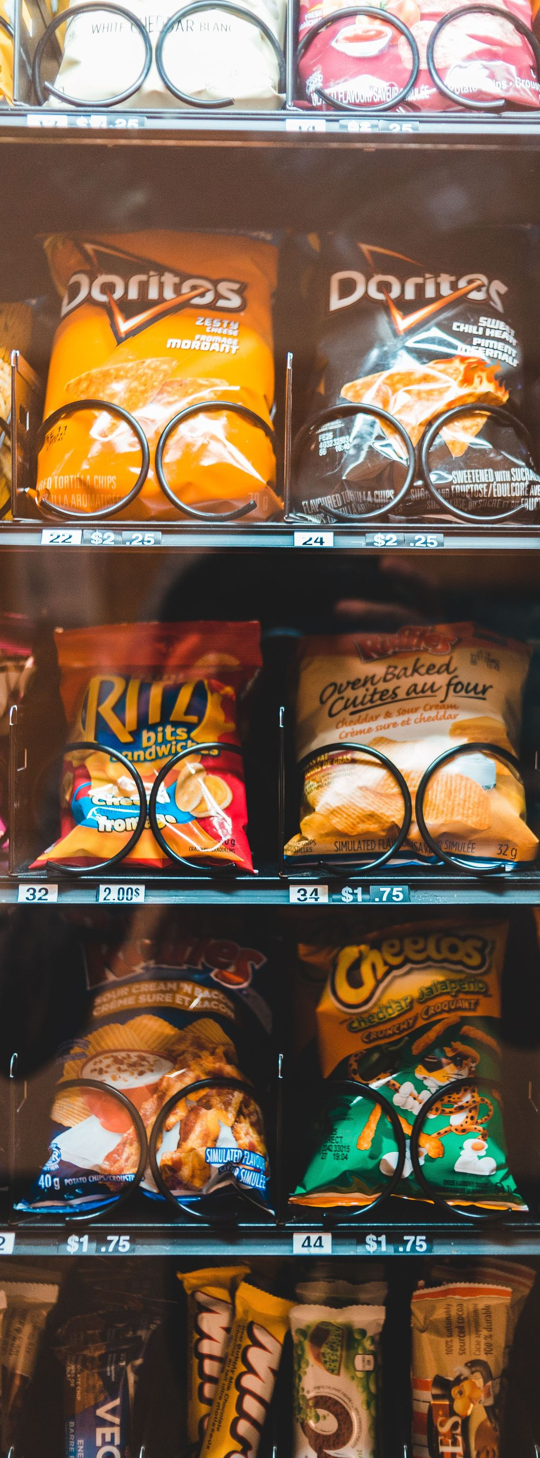 Shelf of assorted Doritos chip bags in orange, black, blue, and green packaging.