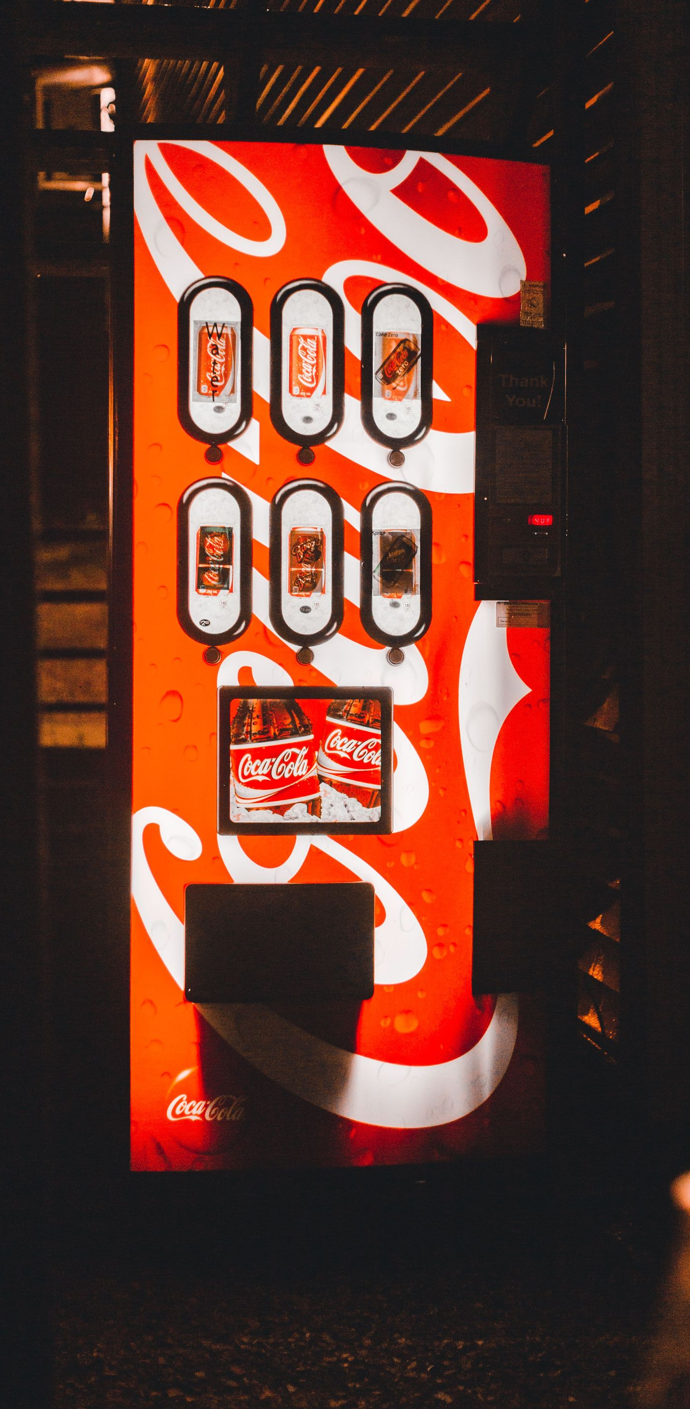 Red vending machine with white swirls glowing in a dark room