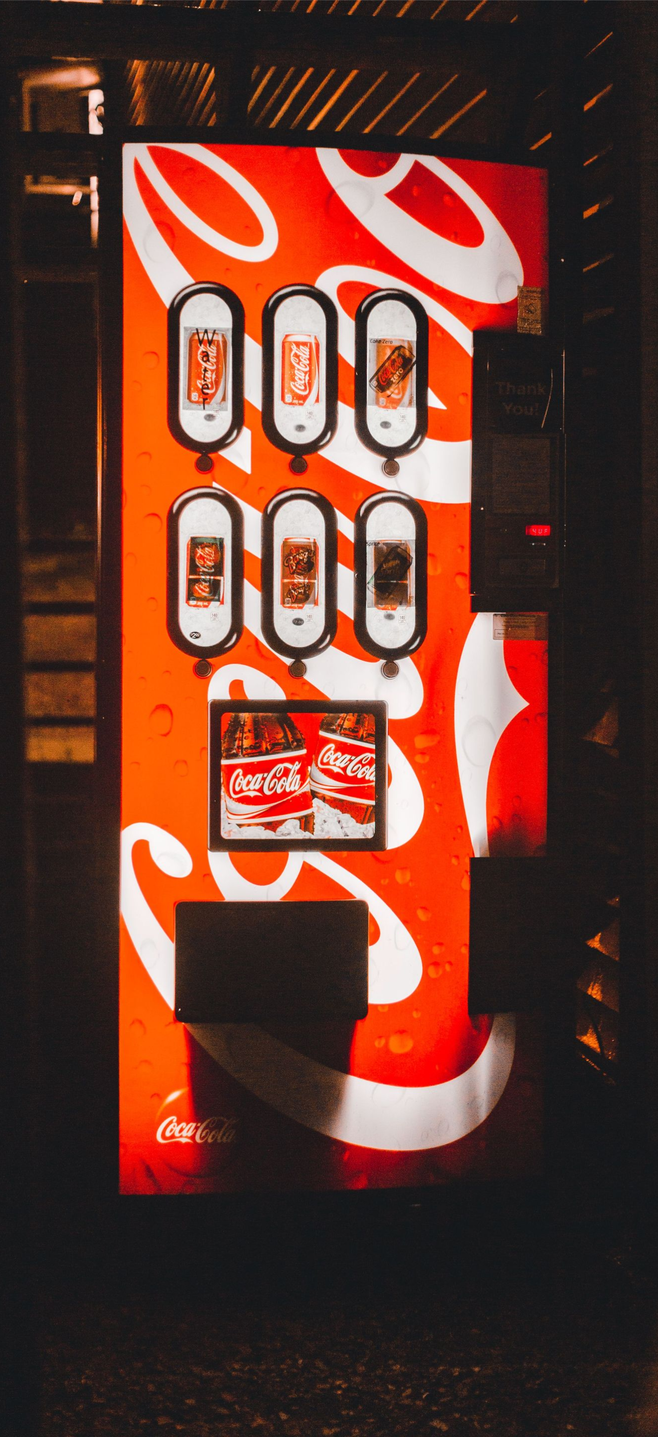 Red vending machine with white designs and multiple small items displayed in a dark setting