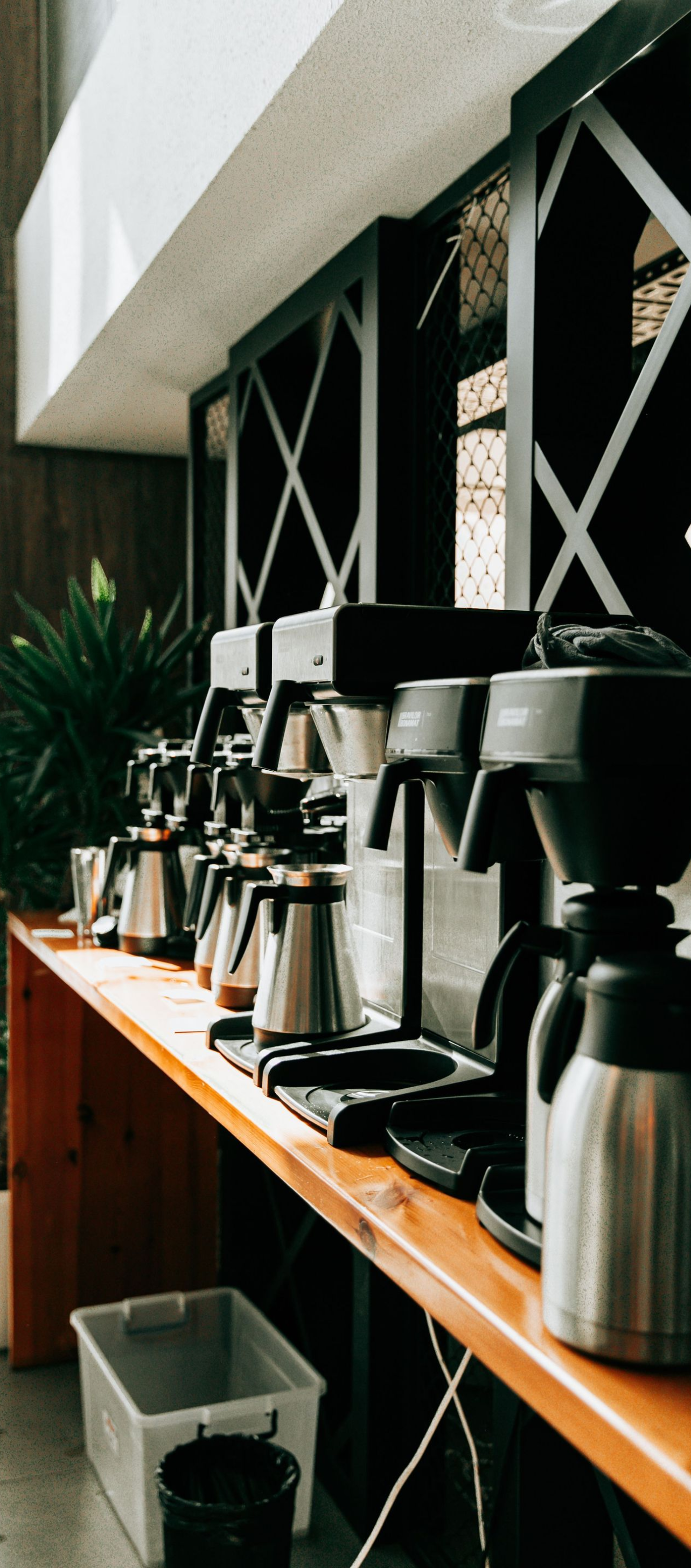 Coffee station with drip machines and carafes on a wooden counter in a modern café