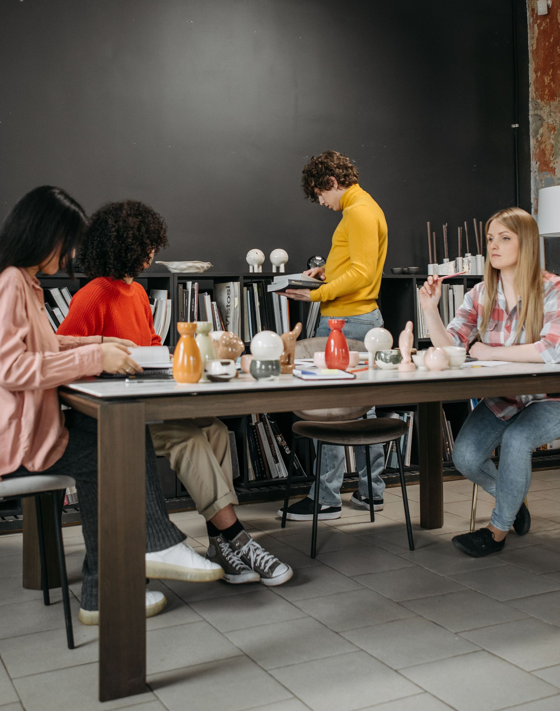 People seated at a café table while a person in a yellow sweater prepares drinks behind it