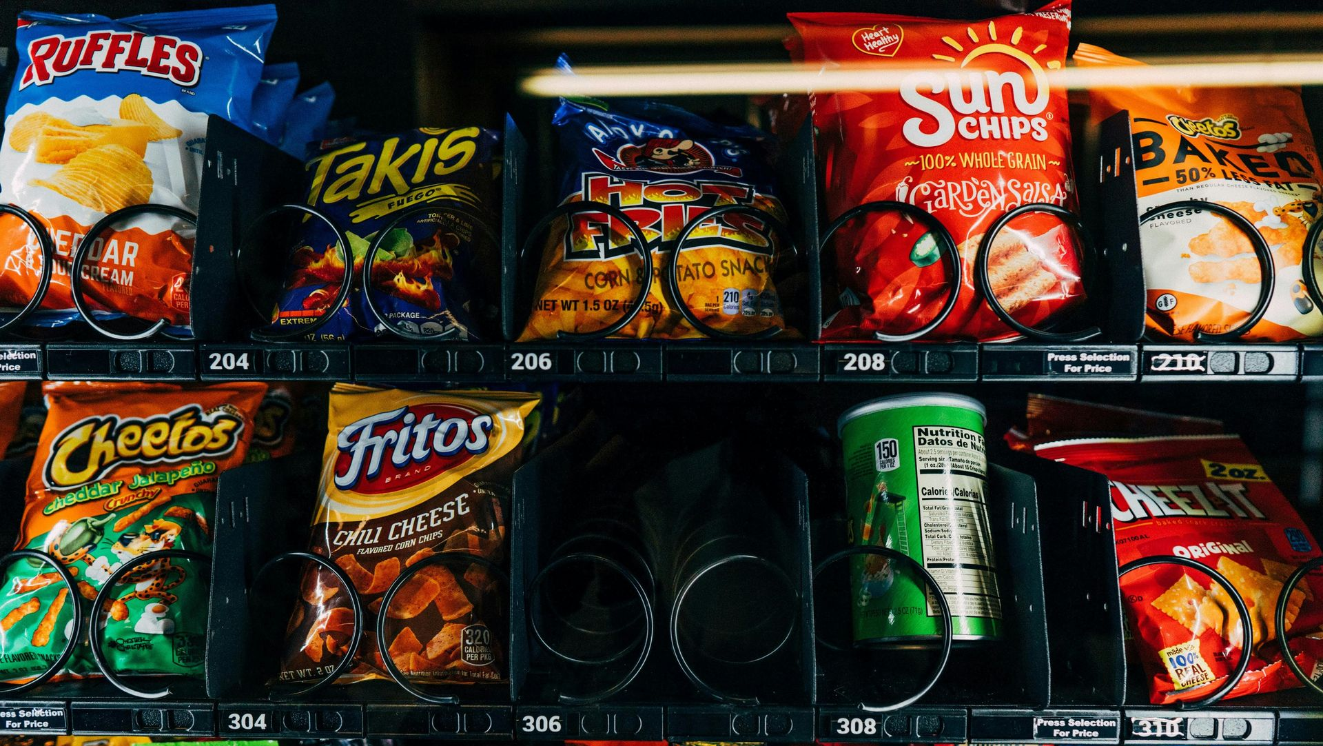 Convenience store snack shelf with colorful chips and a green soda can in the middle row