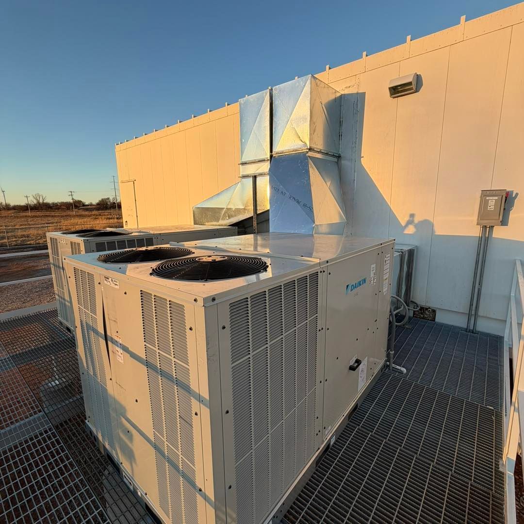 Exterior air conditioning unit on a concrete pad next to a brick wall.