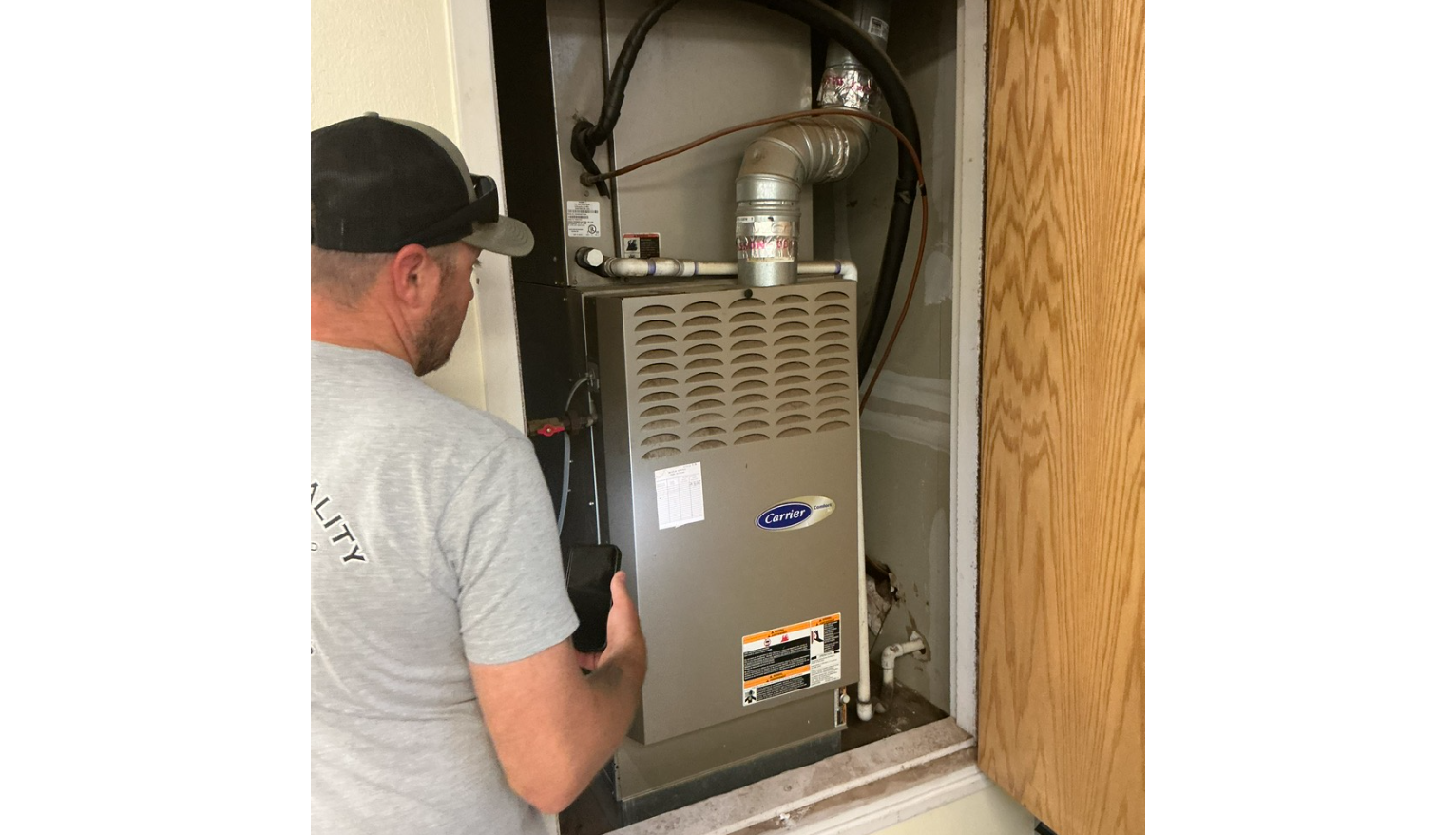 HVAC technician inspecting an outdoor unit with a multimeter.