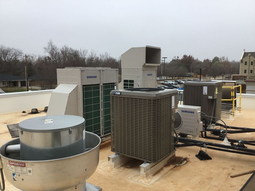Rooftop with HVAC units of varying sizes and shapes against a cloudy sky.