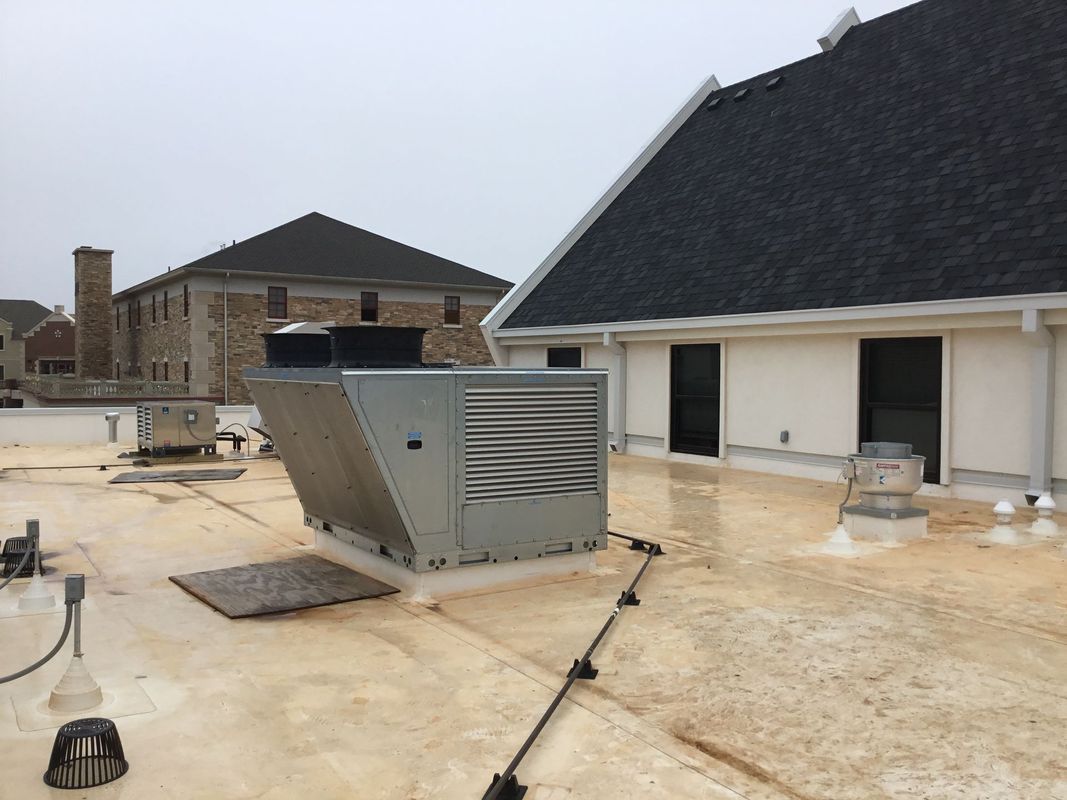 Rooftop view of commercial building, HVAC unit, and black shingle roof, overcast sky.