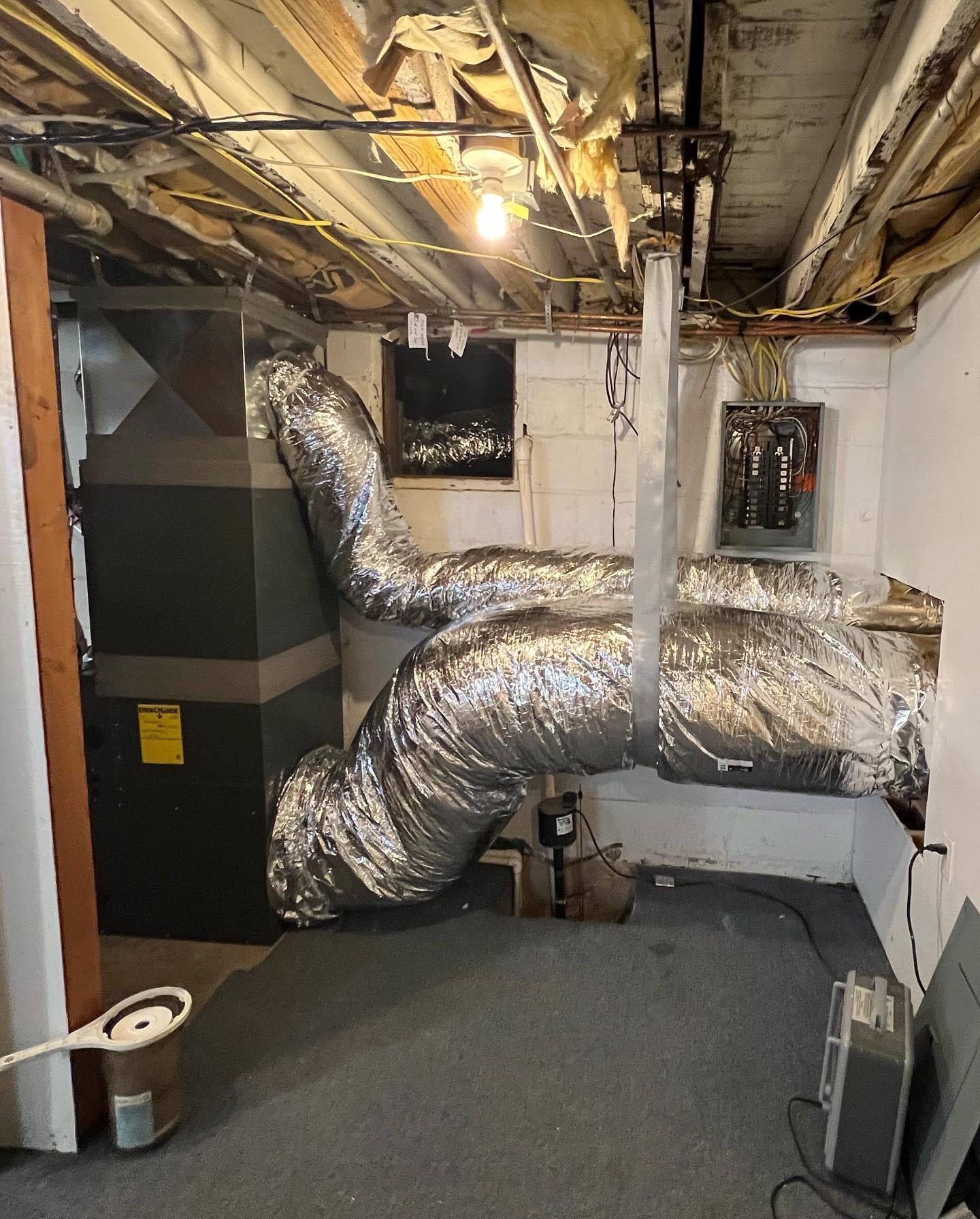 Hands in black gloves using a wrench and screwdriver on copper pipes connected to a boiler.