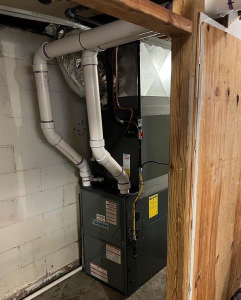 Furnace with white PVC pipes in a basement.