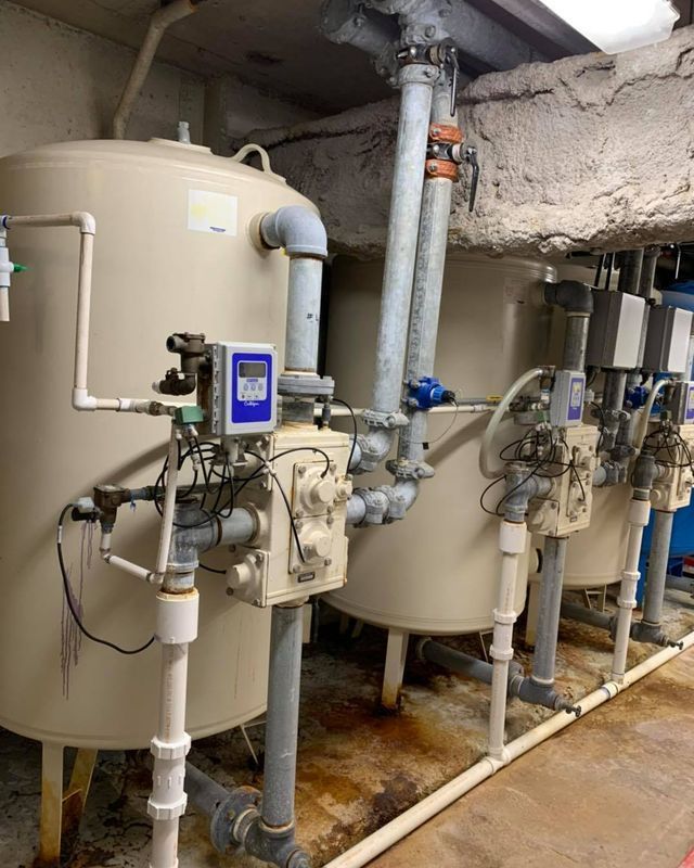 Large beige water tanks with pipes and gauges in an industrial setting.
