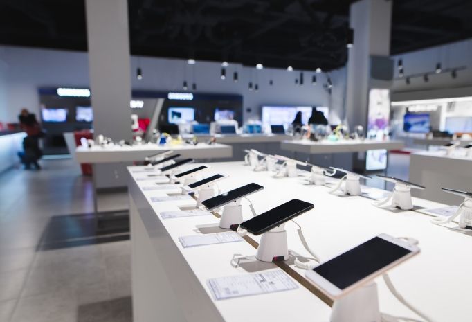 Rows of tablets on display tables in a bright electronics showroom