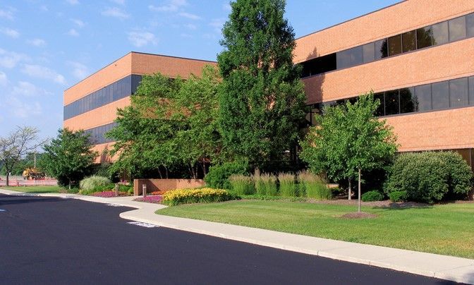 PHFM office building with brick facade, trees, and a paved driveway under a clear sky