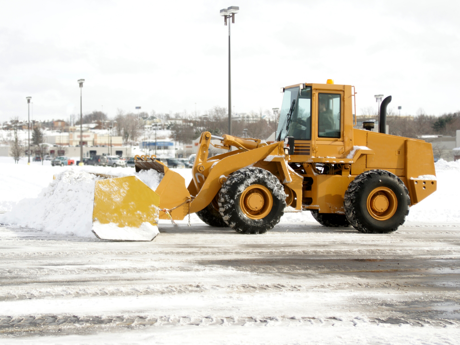 Snowplow clearing a commercial parking lot.