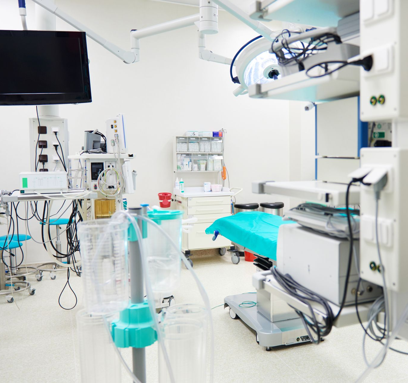 Modern operating room with surgical table, overhead lights, monitors, and medical equipment