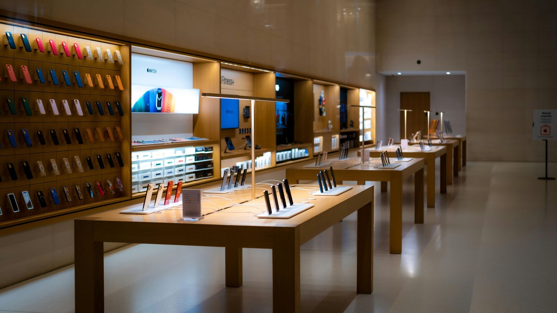 Modern showroom with wooden tables displaying smartphones and electronics under warm lighting