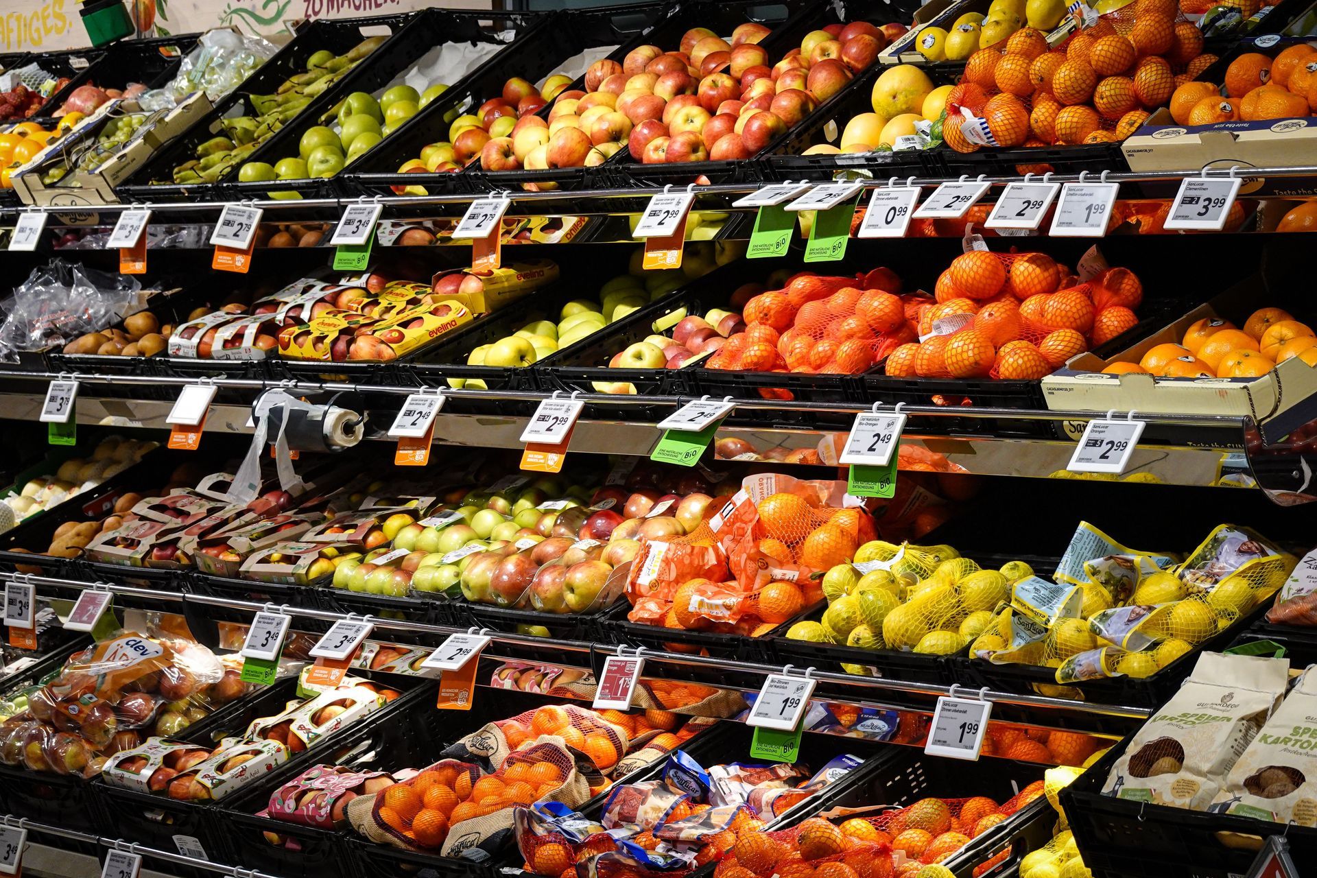 Person shopping in a brightly lit grocery store aisle beside refrigerated shelves