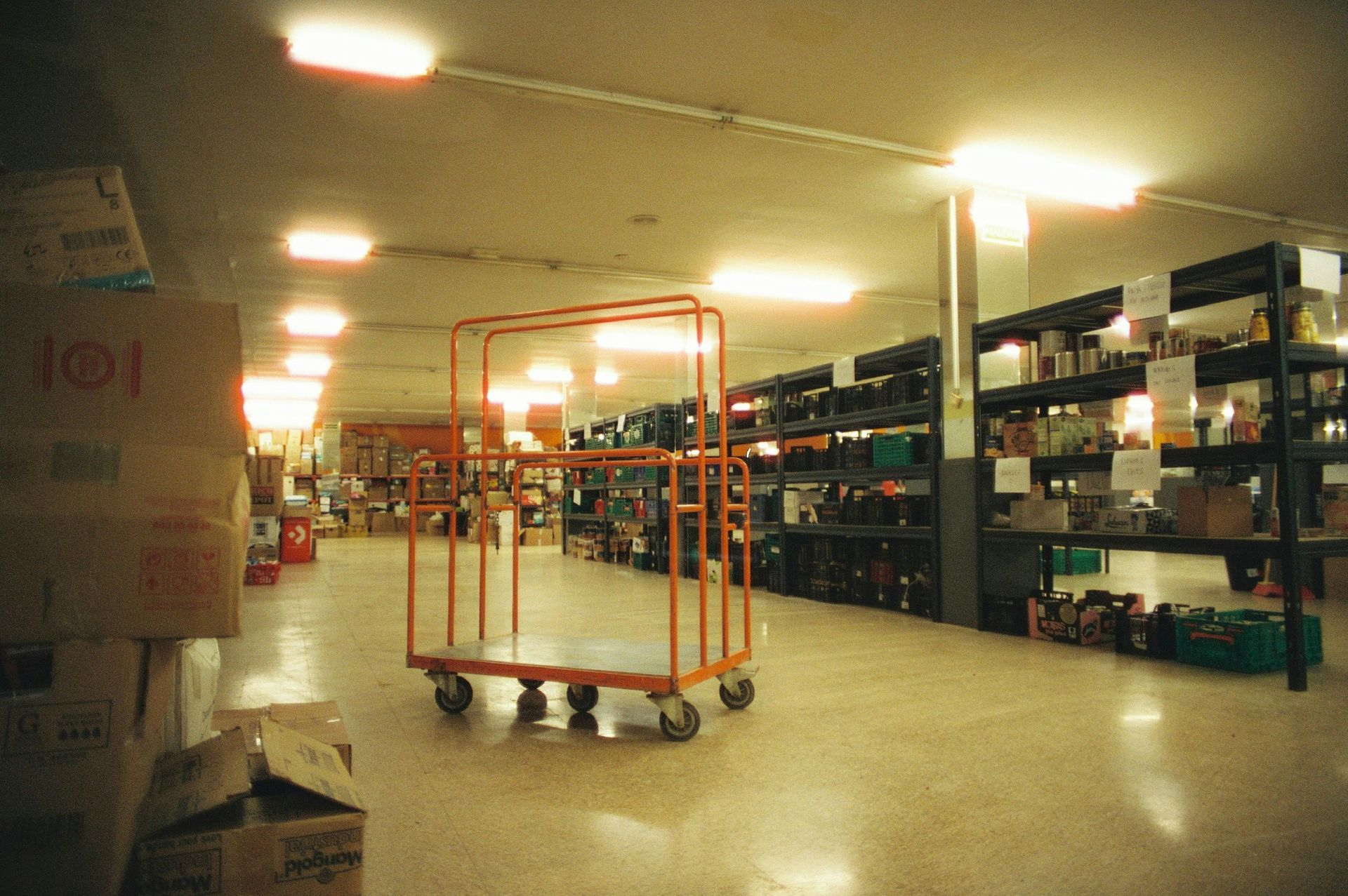 Warehouse aisle with metal shelving and carts under bright ceiling lights