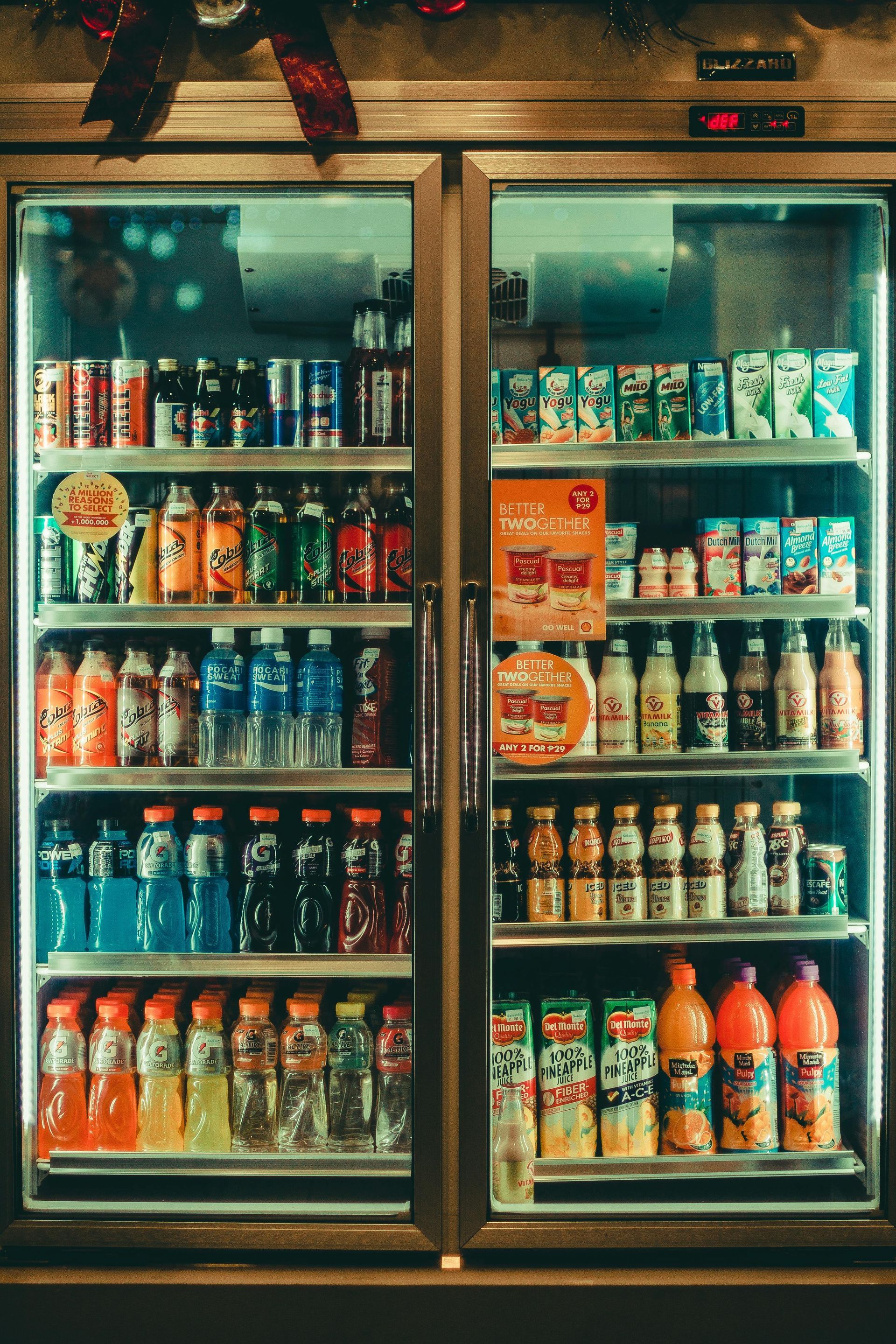 Glass-front beverage cooler stocked with assorted drinks in a dimly lit store