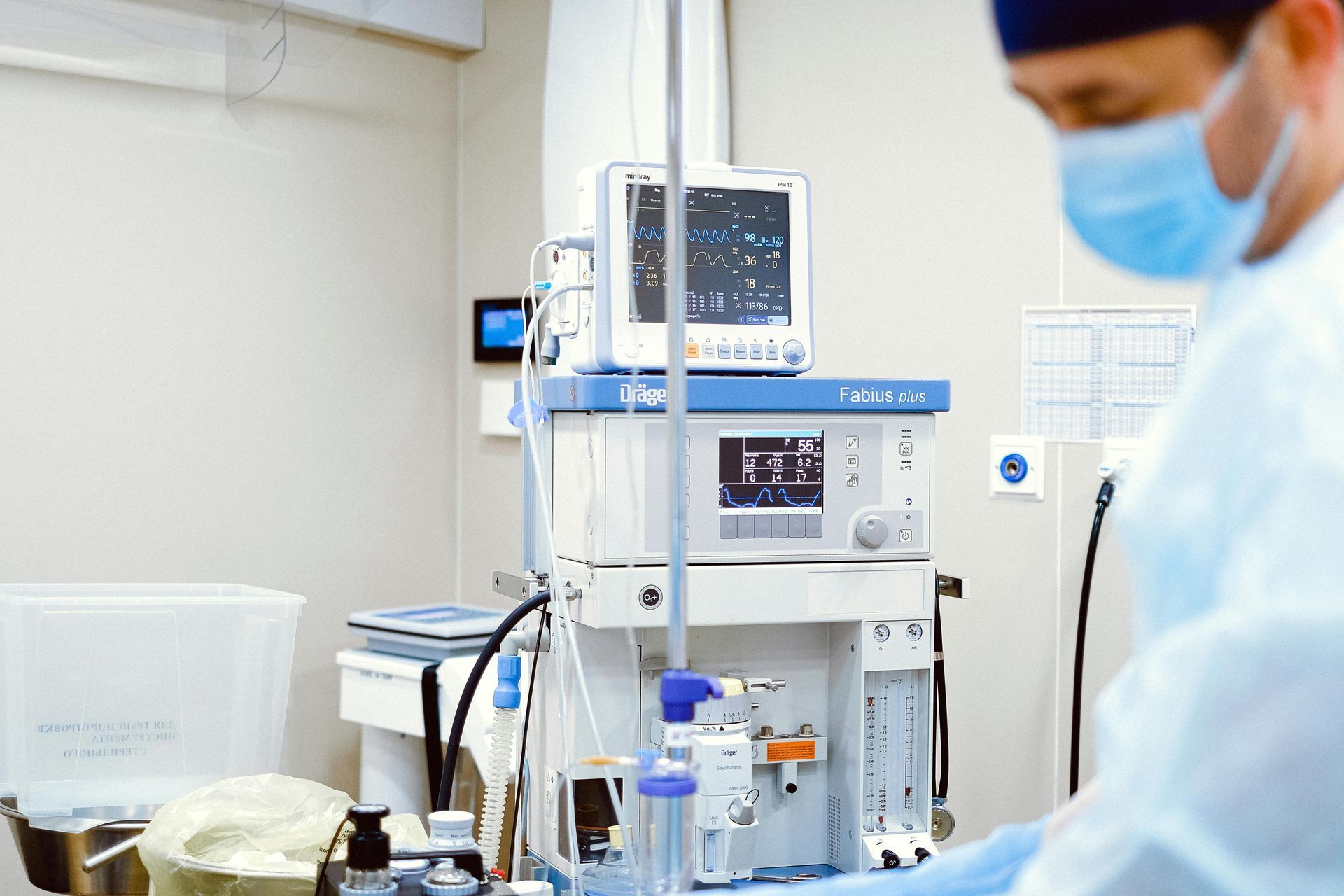 Hospital room with a masked clinician beside a dialysis machine and monitoring equipment