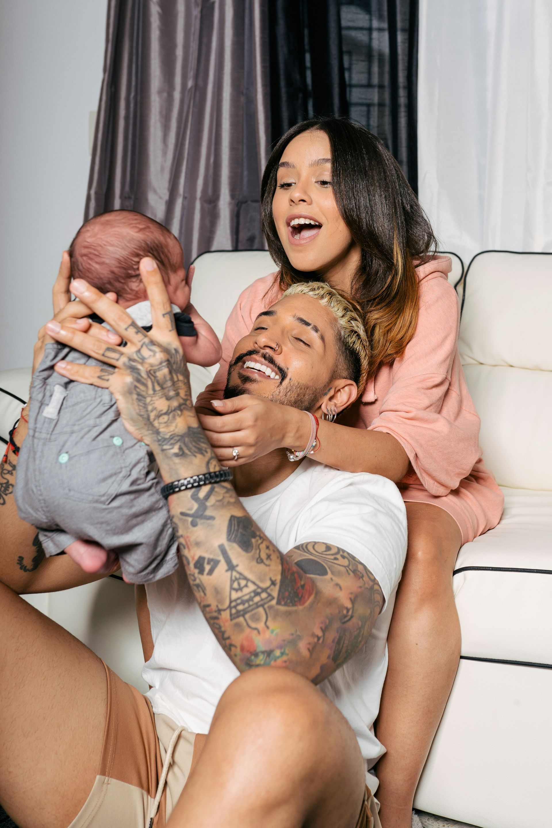 A man and woman are sitting on a couch holding a baby.