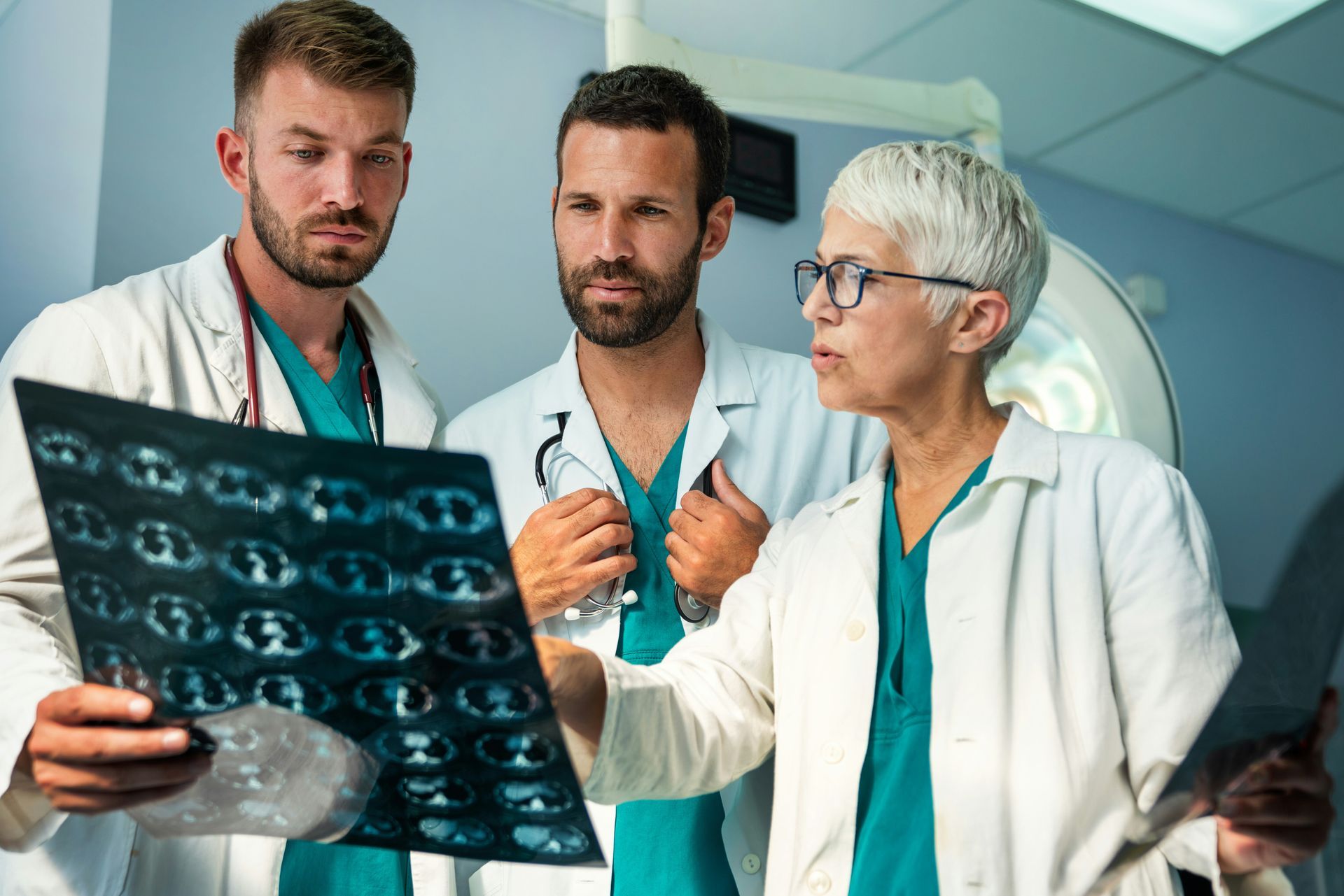 A group of doctors are looking at an x-ray in an operating room.