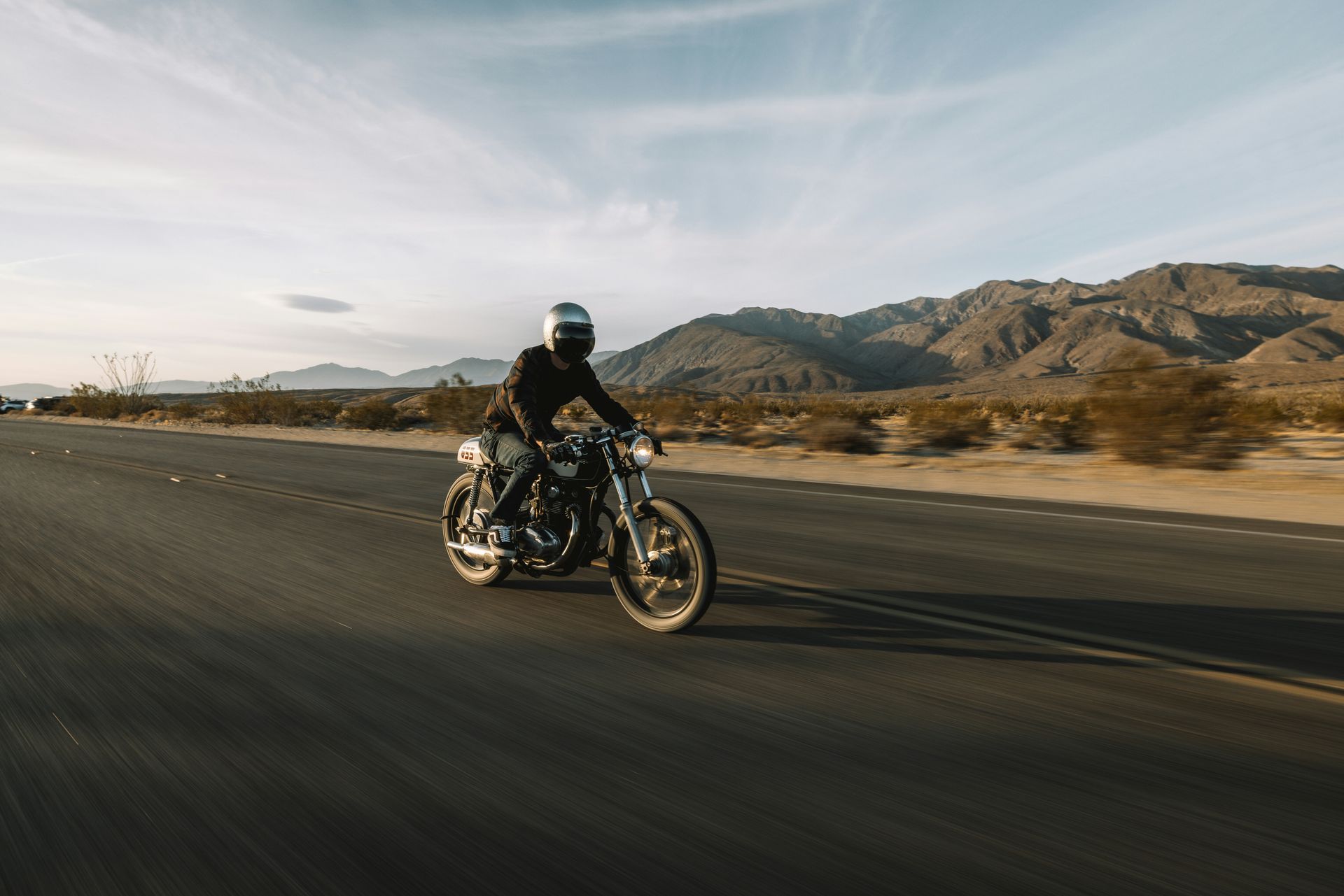 A man is riding a motorcycle down a desert road.