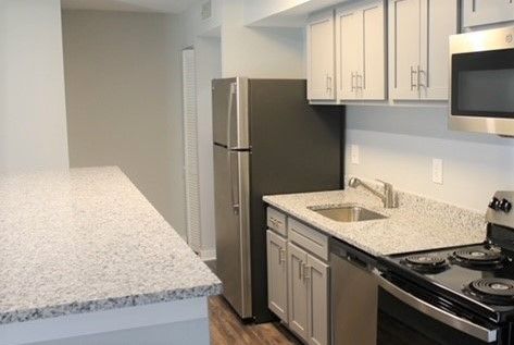 Modern kitchen with white cabinets, speckled countertops, stainless steel appliances, and a stainless fridge.