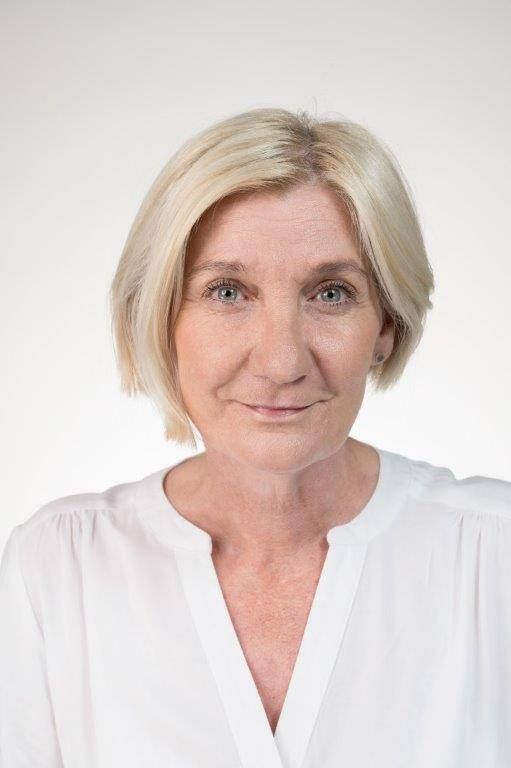 Eine Frau in einem Mickey-Mouse-T-Shirt lächelt in die Kamera.