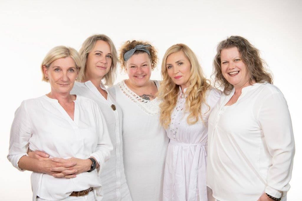 Eine Gruppe von Frauen in weißen Hemden posiert für ein Foto.