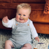 Een lachende baby in een gestreepte overall zwaait, met een voedingssonde.