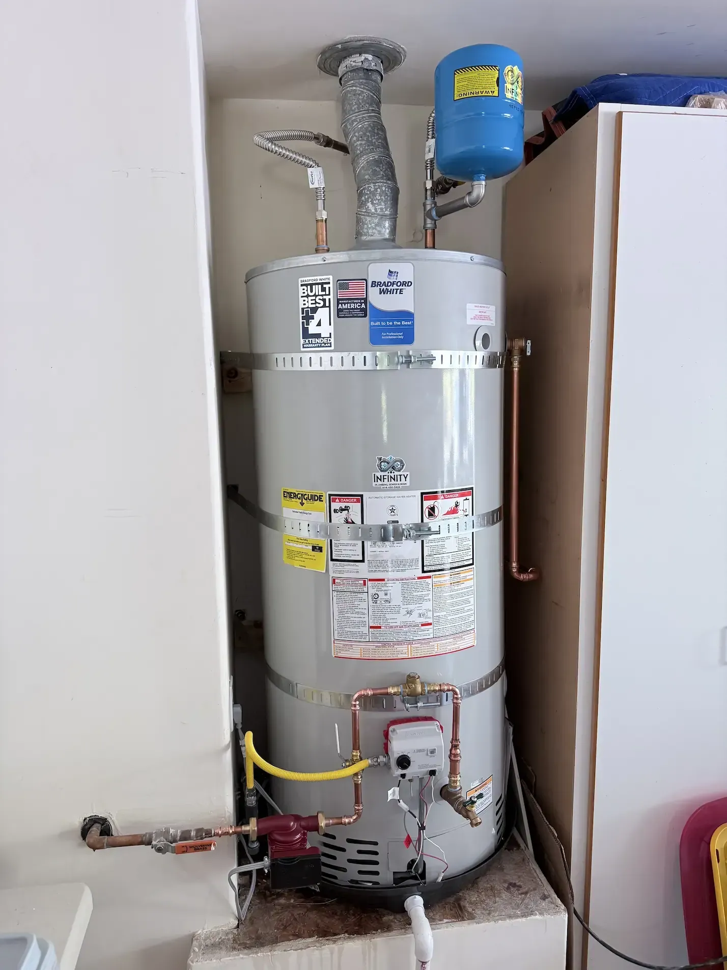 Water heater in a utility closet with pipes, vents, and a blue expansion tank