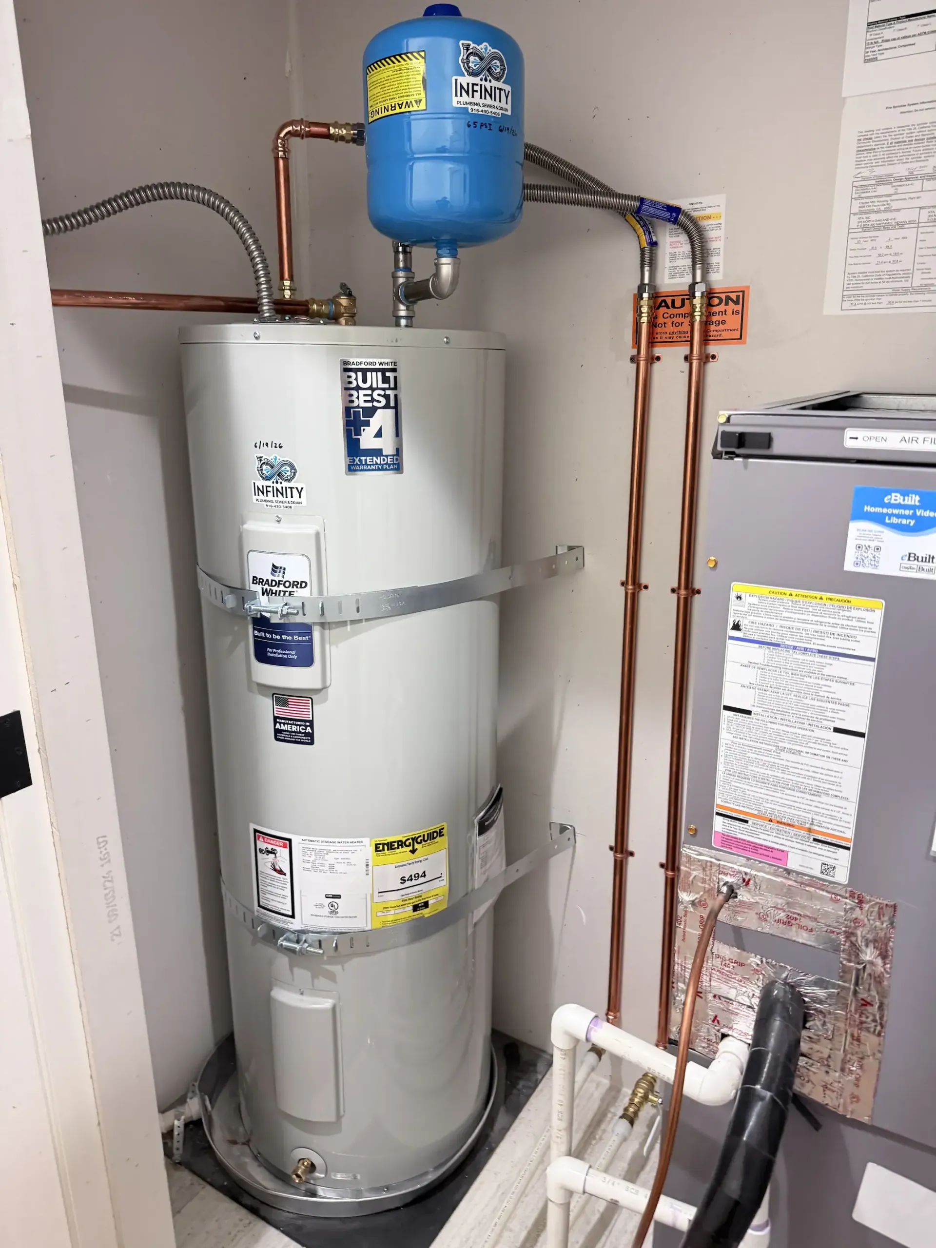 Water heater, expansion tank, and furnace in a utility closet with exposed pipes.