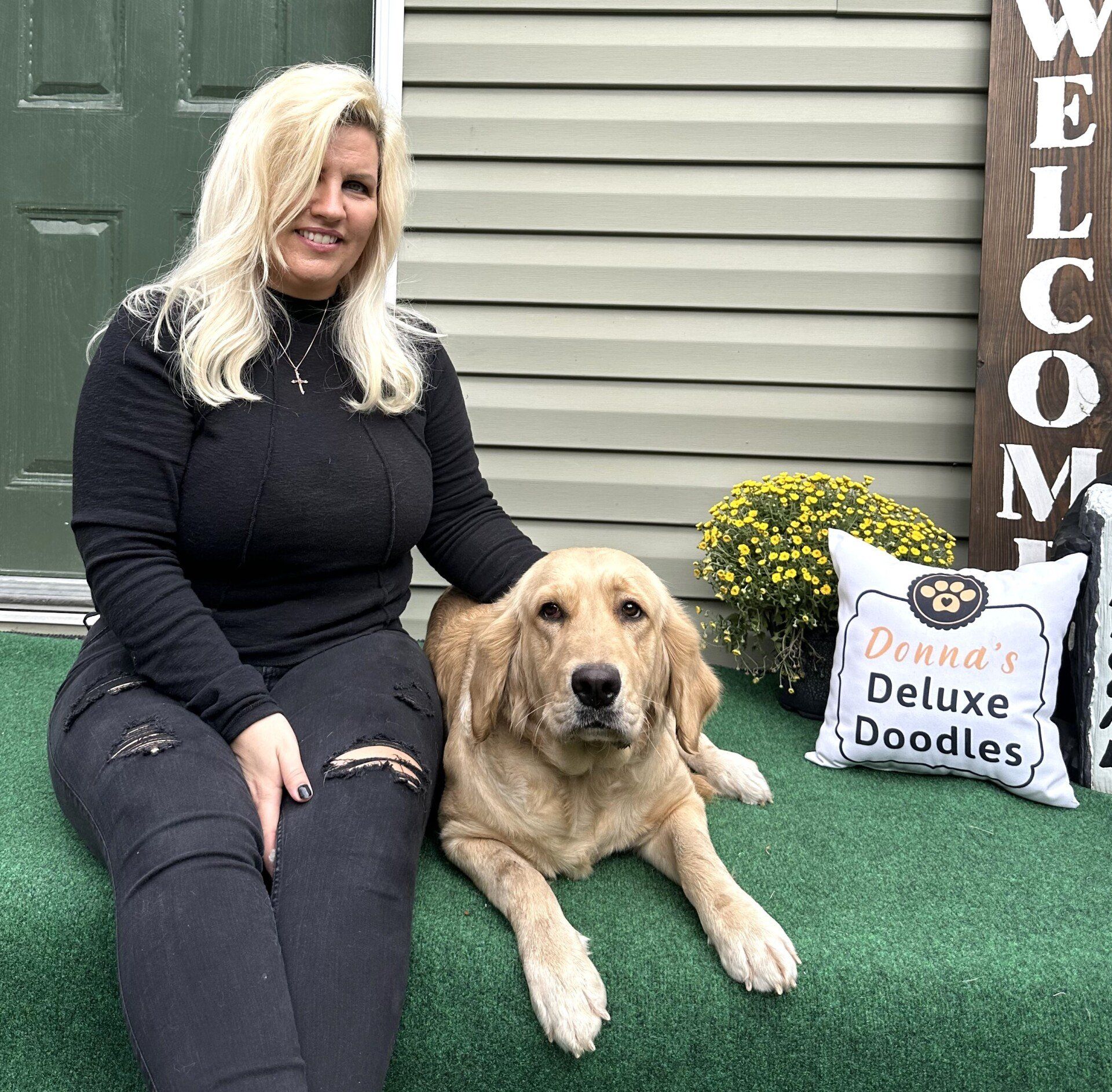 A woman is sitting next to a dog on a porch.