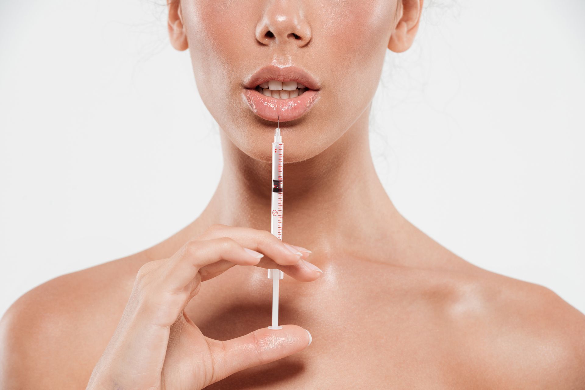 Woman holding syringe near her lips; prepared for injection.