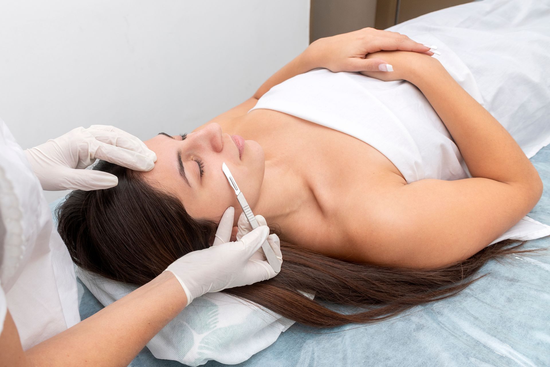 Person receiving a facial injection with gloved hands.