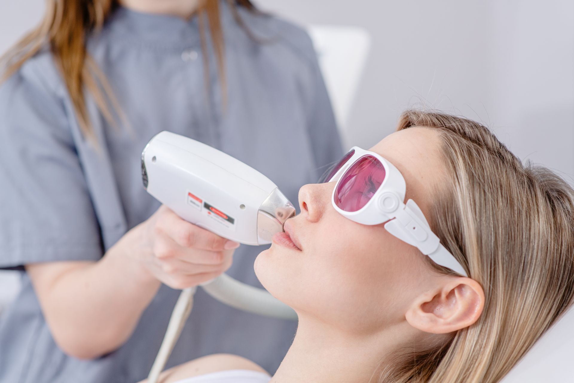 Person receiving laser treatment on face while wearing protective goggles